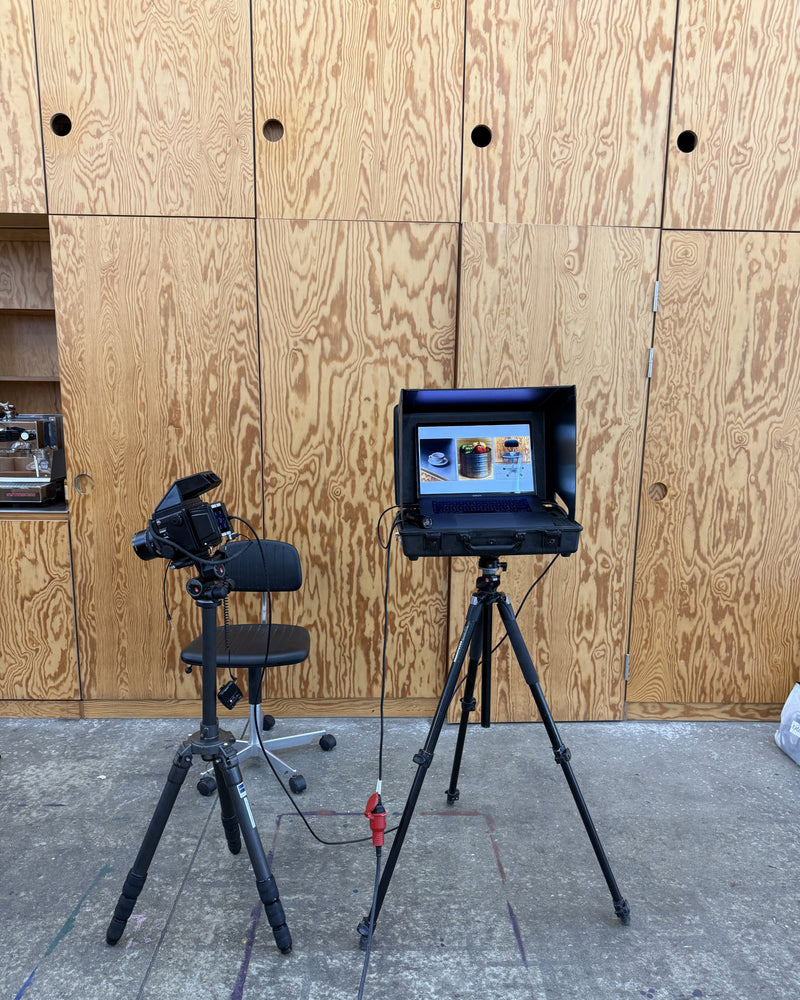 Camera setup with monitor and chair against a wooden wall.